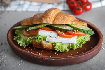 Plate with tasty croissant sandwich on table