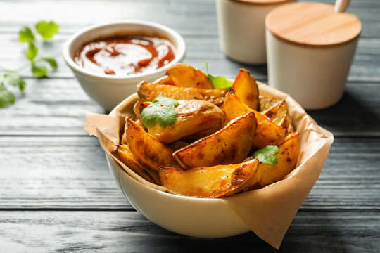 Bowl with tasty potato wedges on table