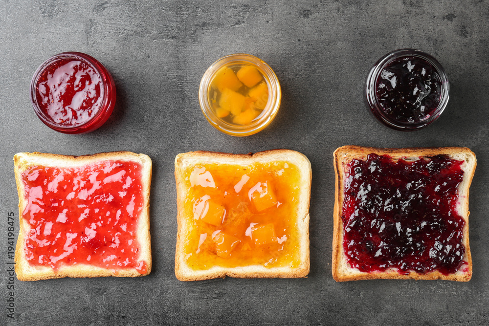 Poster Delicious toasts with various sweet jams on grey background