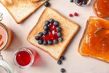 Composition with sweet jams and toasts on wooden background