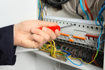 Young electrician repairing distribution board, closeup
