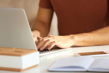 Young man working with laptop in office, closeup