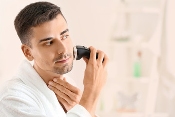 Handsome young man shaving in bathroom