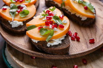Tasty sandwiches with persimmon and cottage cheese on plates