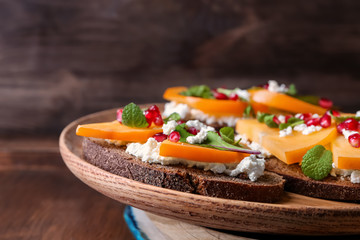 Tasty sandwiches with persimmon and cottage cheese on plates
