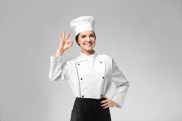 Portrait of female chef on grey background