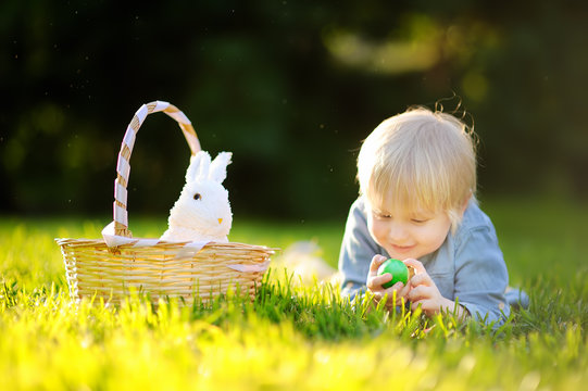 Charming little boy hunting for easter egg in spring park on Easter day
