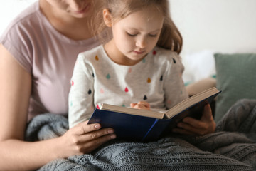Fototapeta na wymiar Religious Christian girl reading Bible with mother indoors