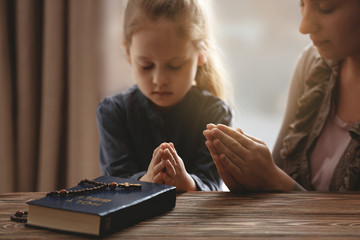 Religious Christian girl praying with her mother indoors © Africa Studio