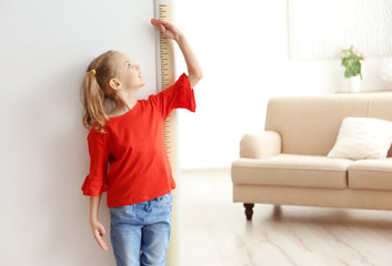 Little girl measuring height near door at home