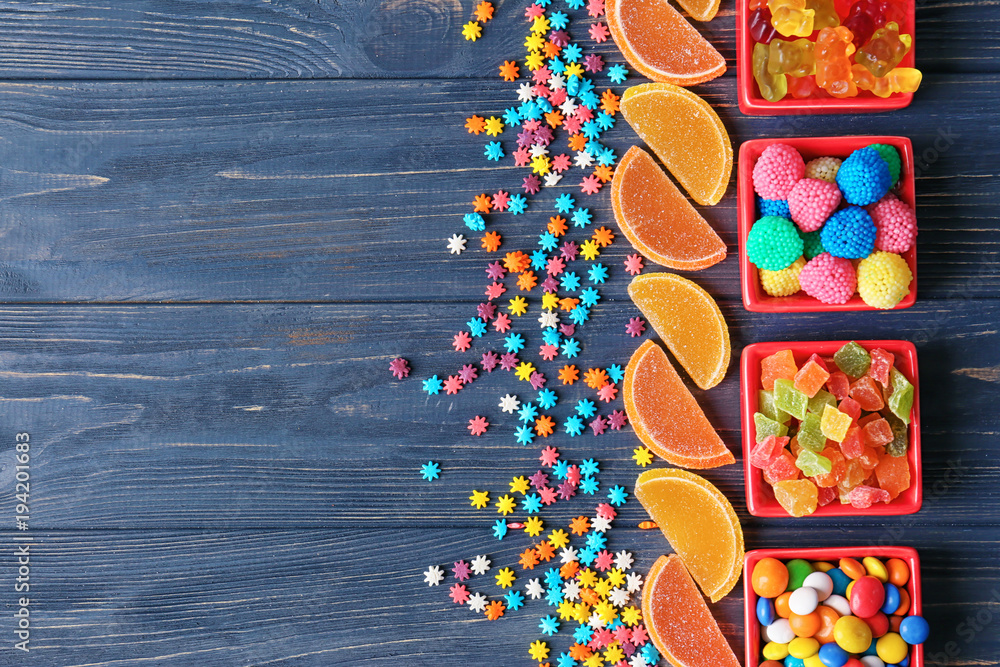 Sticker Colorful candies on wooden background, flat lay