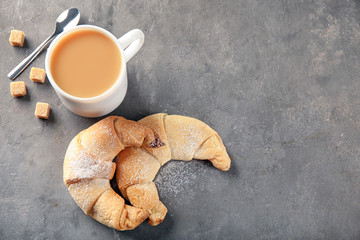 Tasty crescent rolls and cup of coffee on grey background