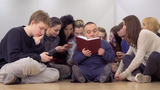 Group of young people sets aside their phones and start reading the book