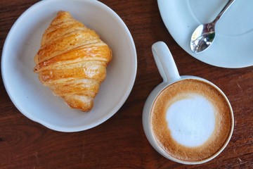 Coffee cup hot and croissant in the morning on wooden table