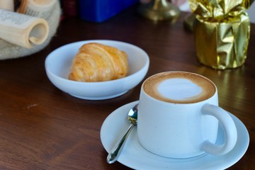 Coffee cup hot and croissant in the morning on wooden table