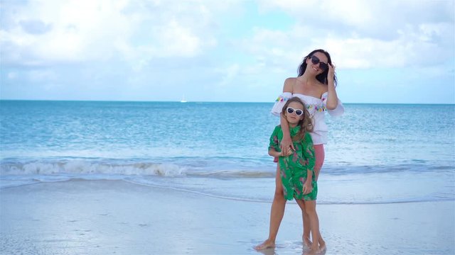 Beautiful mother and little daughter on Caribbean beach playing together