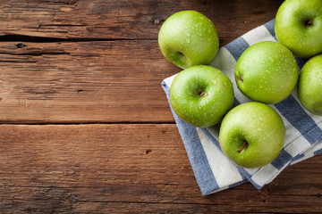 Ripe green apples in a wooden bowl on an old rustic table. Useful fruits on wooden background. Top view with copy space