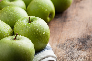 Ripe green apples in a wooden bowl on an old rustic table. Useful fruits on wooden background. with copy space