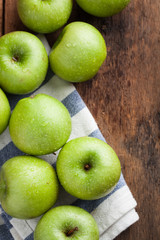 Ripe green apples in a wooden bowl on an old rustic table. Useful fruits on wooden background. Top view