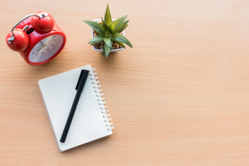 Wood office desk table with laptop,notebook and pen,and time clock alarm,Top view with copy space, flat lay.