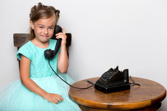 A little girl is ringing on the old phone.