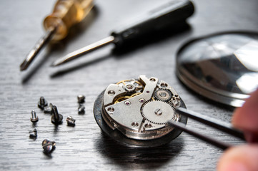 Old watch repair composition with magnifier and screwdrivers. A watchmaker repairs