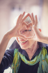 Cute senior old woman making a heart shape with her hands and fingers - 194205690