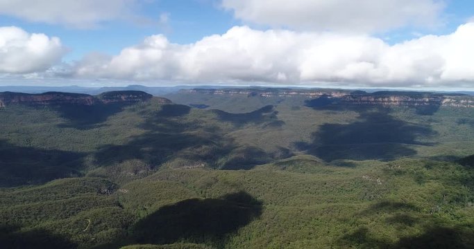 Eroded sandstone cliffs dubbed Three Sisters off Katoomba town in Blue Mountains in wide panorama view over canyon, Mount Solitude and rim of mountains.
