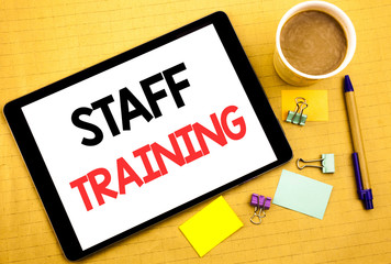 Conceptual hand writing text caption showing Staff Training. Business concept for Teaching or Education Written on tablet laptop, wooden background with sticky note, coffee and pen
