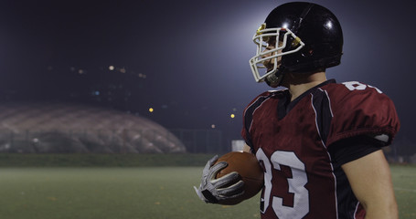 American football player holding ball while running on field