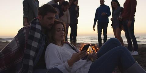 Couple enjoying bonfire with friends on beach