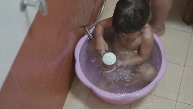 Asian boy about 2 years being washed and showered by his mother
