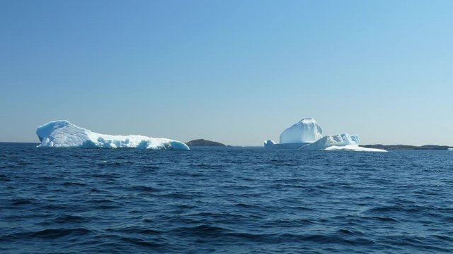 Beautiful large icebergs float in arctic blue water at twillingate
