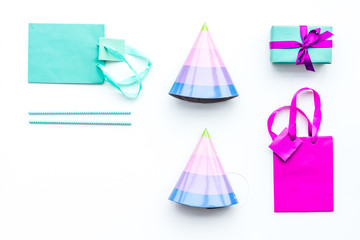 Birthday party accessories. Gift box, paper bag, party hat on white background top view copy space