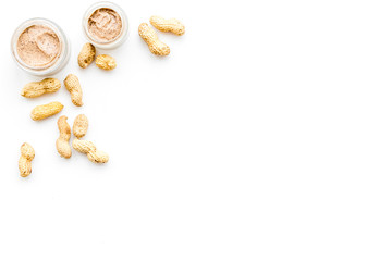 Natural cosmetics for skin care. Body scrub with peanut. White background top view copy space
