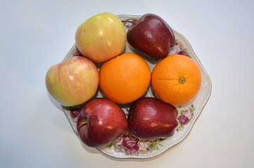 A dish of fruit. Ripe apples and oranges. even an image with these fruits causes salivation. they so ask, give up fast food and eat us 