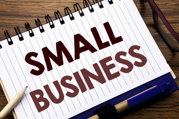 Fototapeta premium Hand writing text caption inspiration showing Small Business. Business concept for Strategy Management Written on notebook note paper, wooden background with glasses pen and marker.