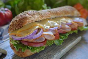 Sub sandwich with melted cheese on a cutting board