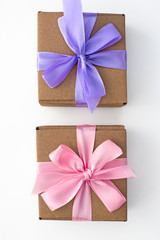 Two holiday gift boxes tied with satin ribbon on white background.