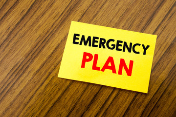 Hand writing text caption inspiration showing Emergency Plan. Business concept for Disaster Protection written on sticky note paper on the wooden keyboard background. Empty table.