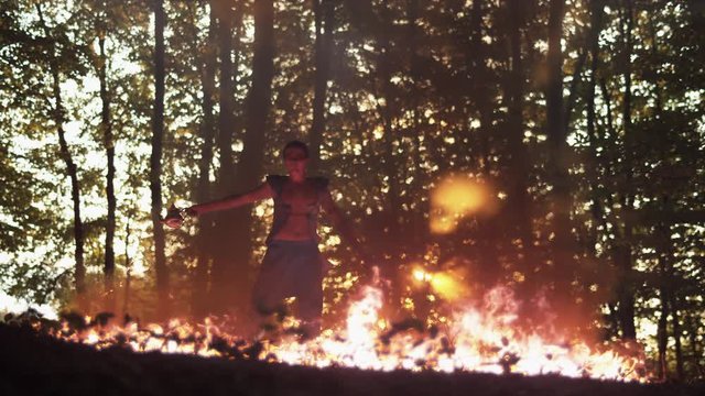 Man performing behind the flames in the woods