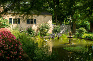 Obraz premium A small pond in a garden with a water fountain in it.