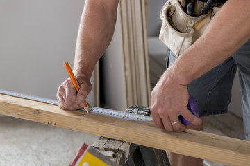 close up male constructor carpenter or builder hands detail working and measuring wood in industrial construction job concept