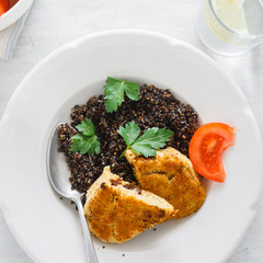 Vegetarian dinner table. Plate with black quinoa and oatmeal cutlets with prunes on white wooden table close up
