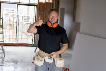 attractive and confident constructor carpenter or builder man with ear protection gear working...