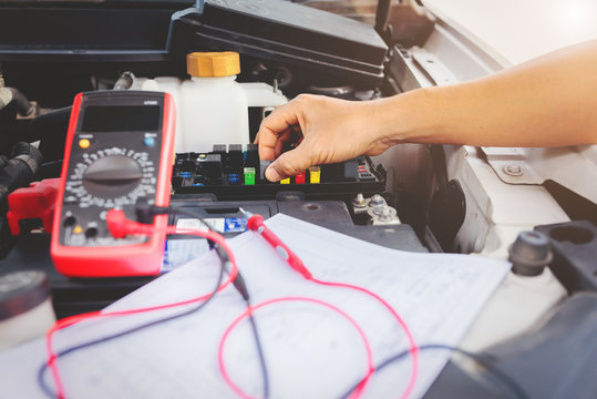 Auto mechanic using digital multimeter to check the fuse in a car,check voltage level car battery.