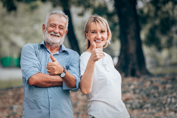 Senior couple showing thumbs up in park ,Nature background