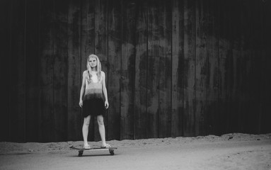 Teenage girl alone on skateboard with thoughtful look on her face in black and white