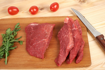 Sliced raw beef on cutting board and vegetables