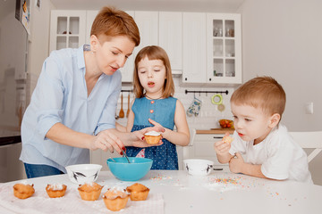 Children sprinkle cupcakes with colored caramel for Easter and eat.